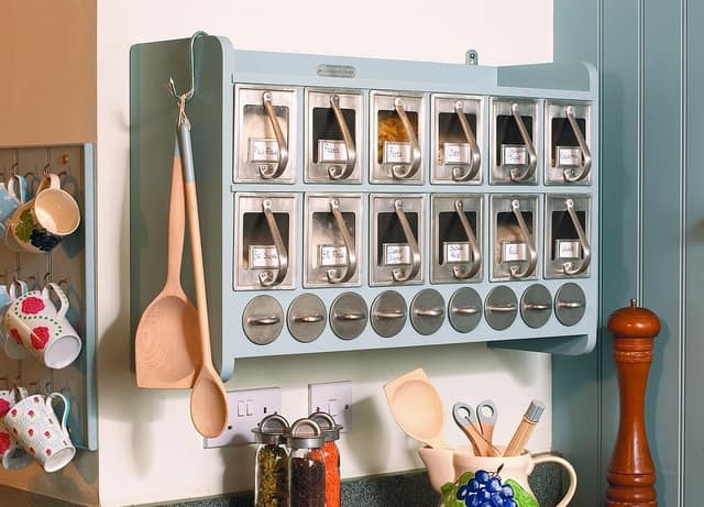 Light blue spice rack with hooks on the side for hanging utensils