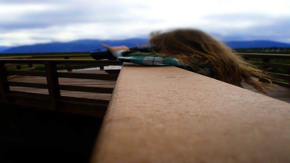 Image of a girl on a lookout bridge observing a scene through binoculars