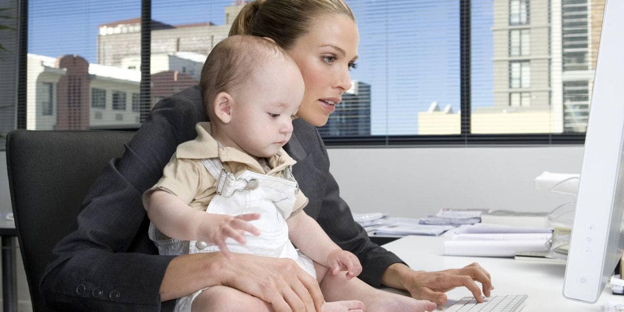 Baby sitting on desk of a businesswoman