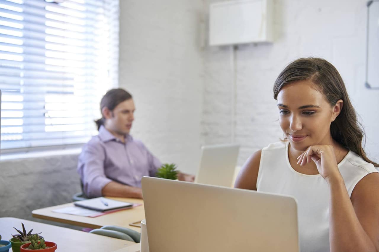 beautiful young business woman working on laptop computer at office desk