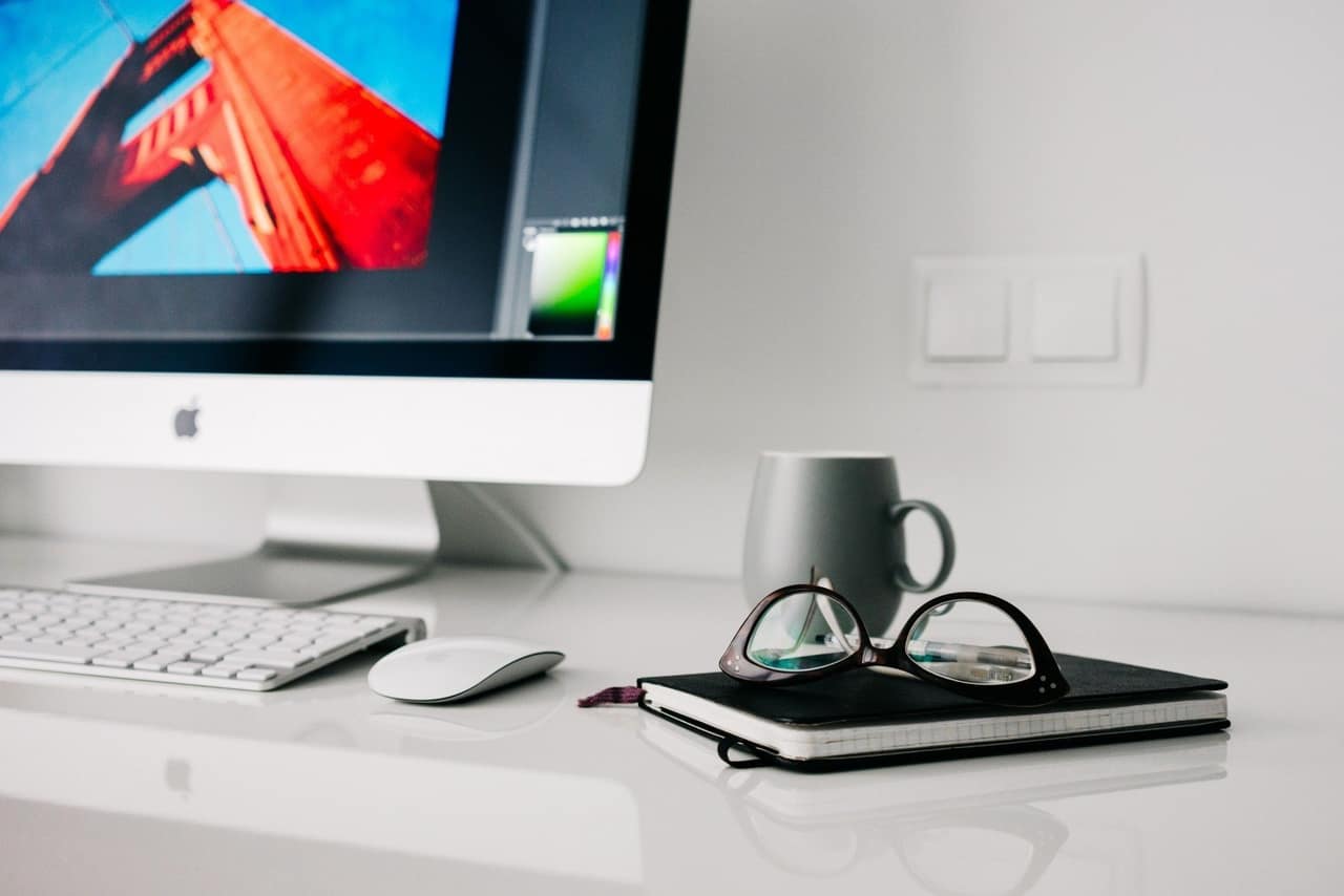 Office desktop computer with mug and glasses