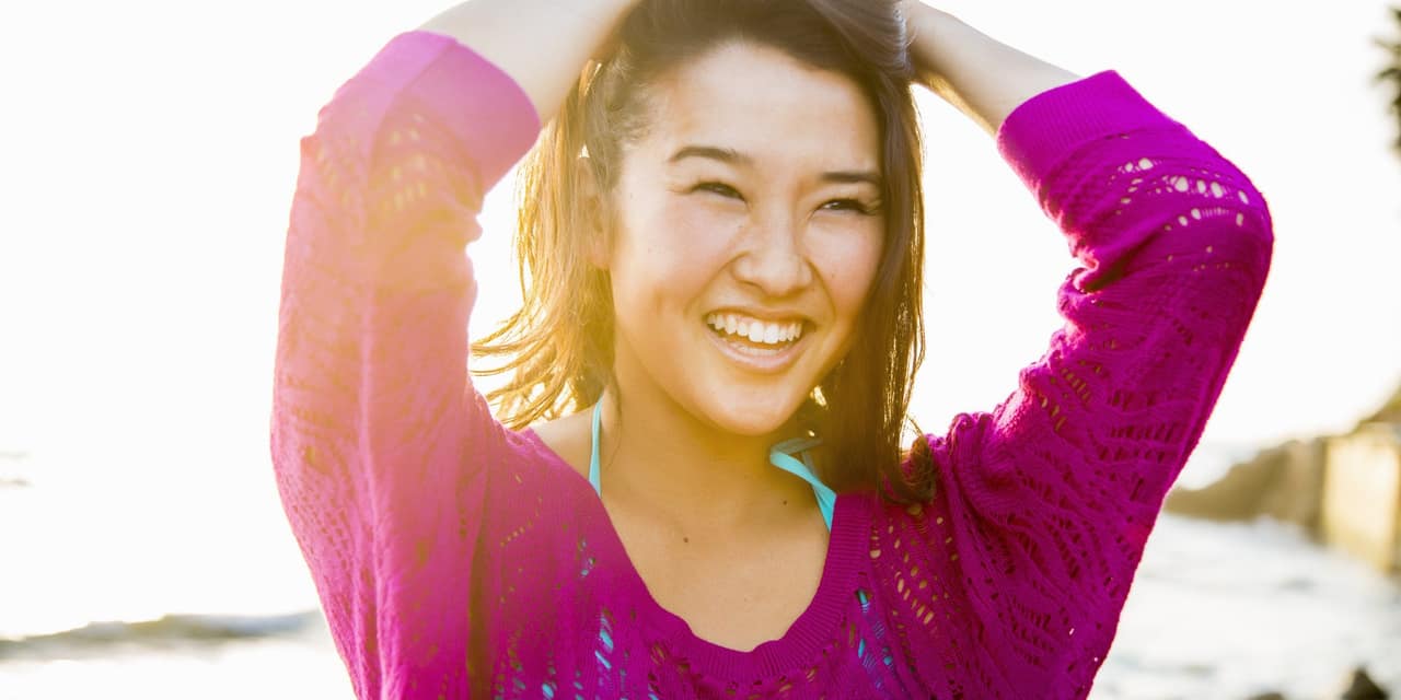 Beautiful woman at beach at sunset laughing