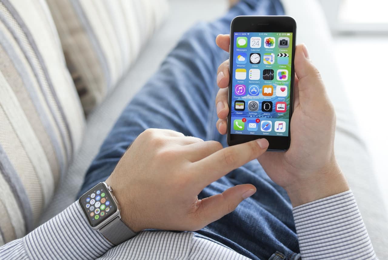 Alushta, Russia - September 24, 2015: Man hand with Apple Watch holding iPhone. Apple Watch was created and developed by the Apple inc.
