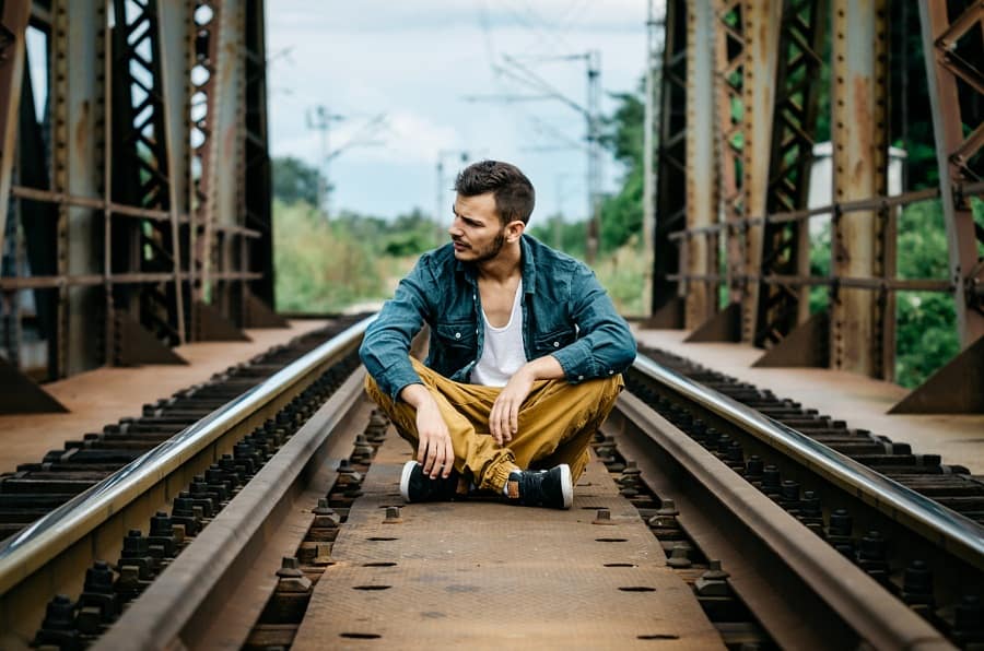 Portrait of young man sitting on the railroad bridge. Vintage Instagram style effect, soft and selective focus, shallow DOF, grain texture visible on maximum size