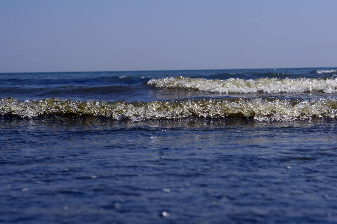 Miniature 2 inch waves crashing on a calm sea, with copy space