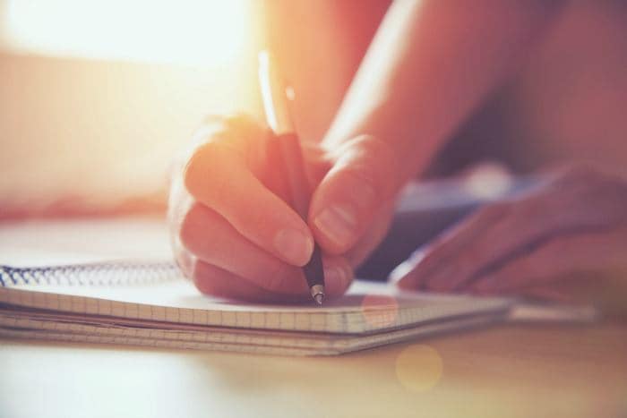 female hands with pen writing on notebook