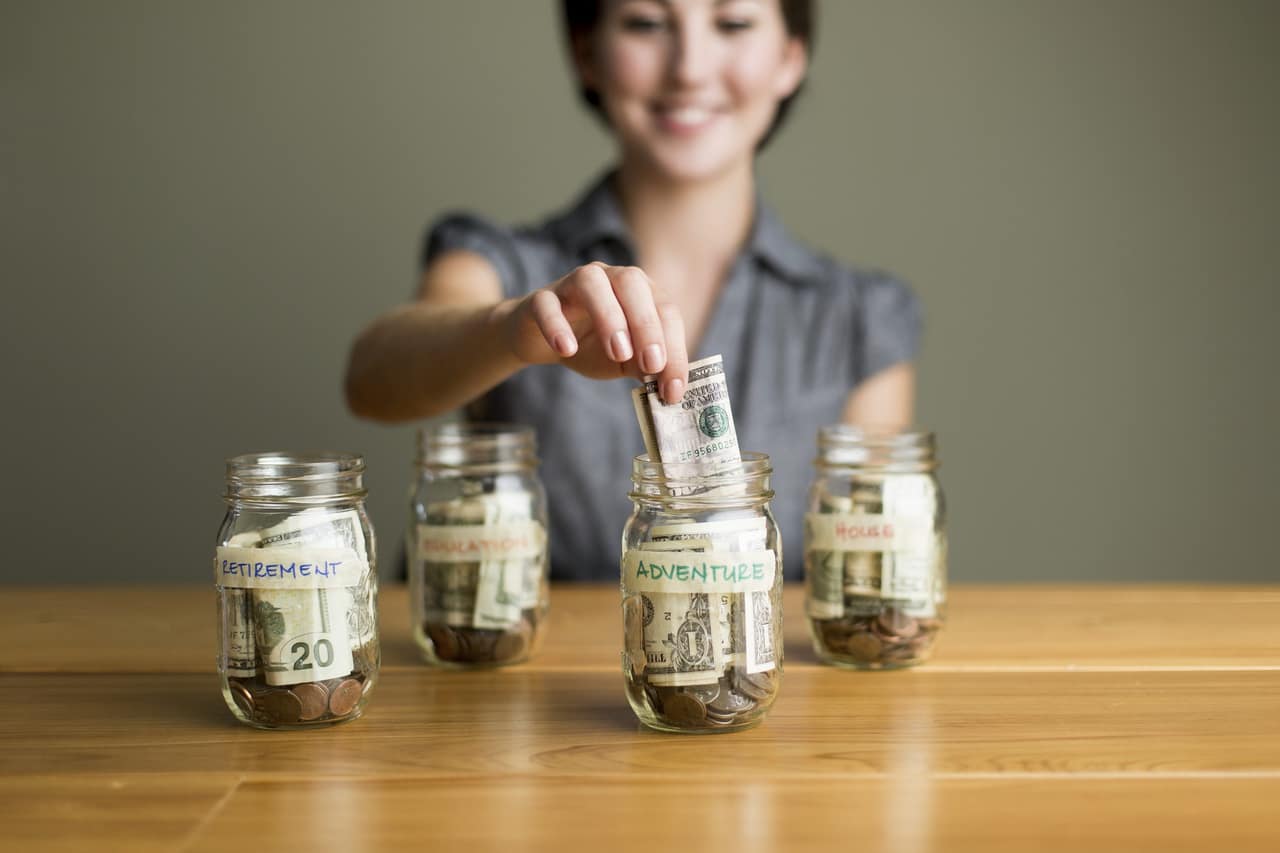 A happy woman saving in jars.