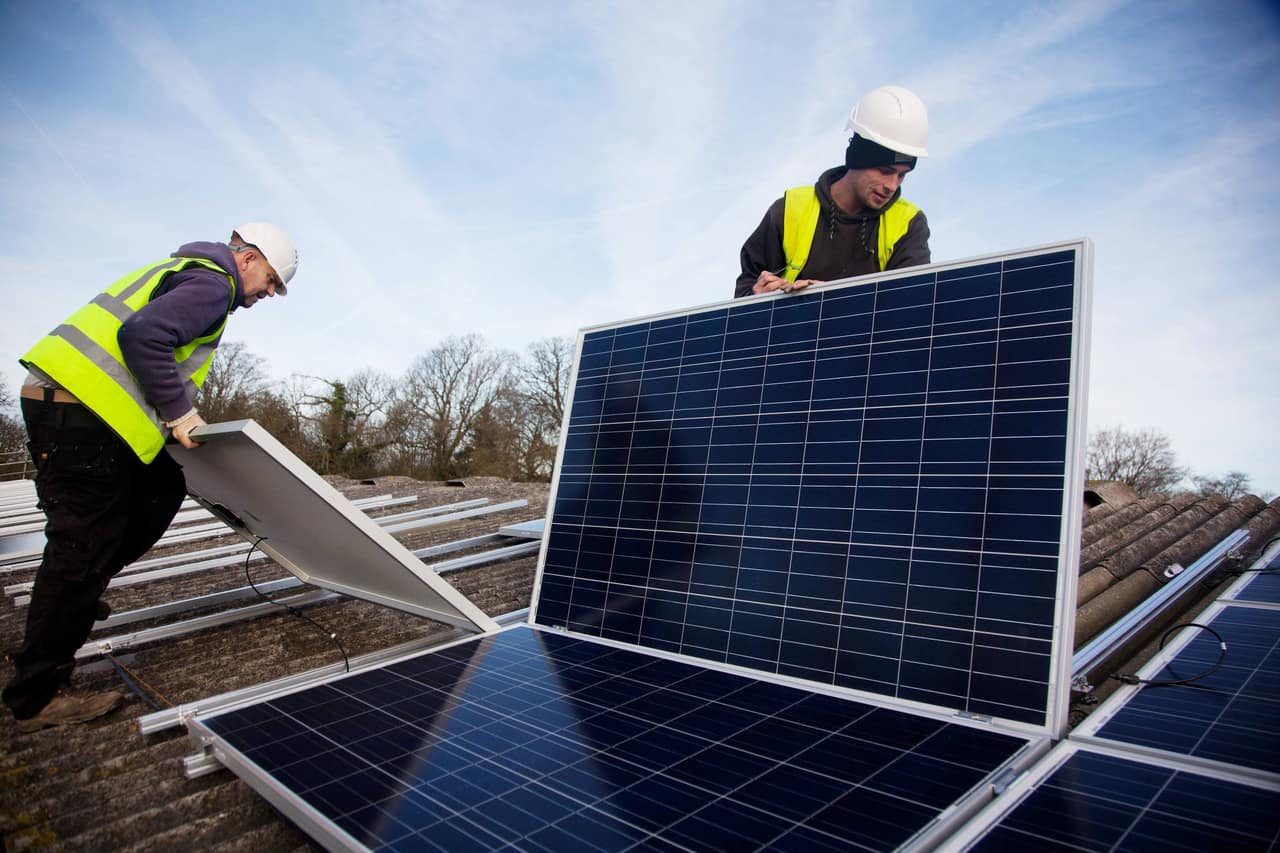 Andy Tyrrell and Jake Beautyman install solar panels on a barn roof on Grange farm, near Balcombe.