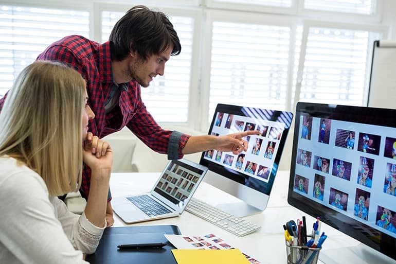 Male and female graphic designers interacting over computer in office