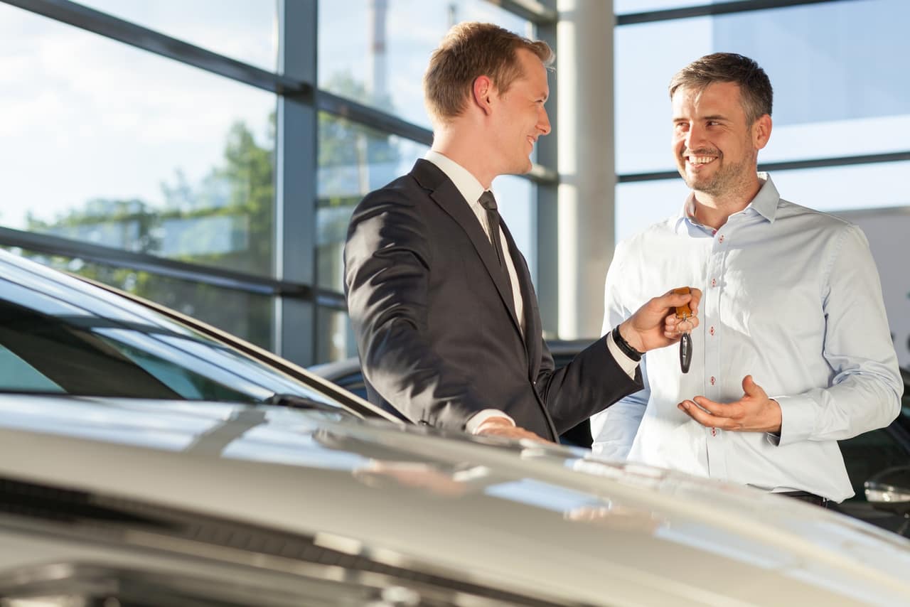 Photo of car dealer selling car to happy handsome buyer
