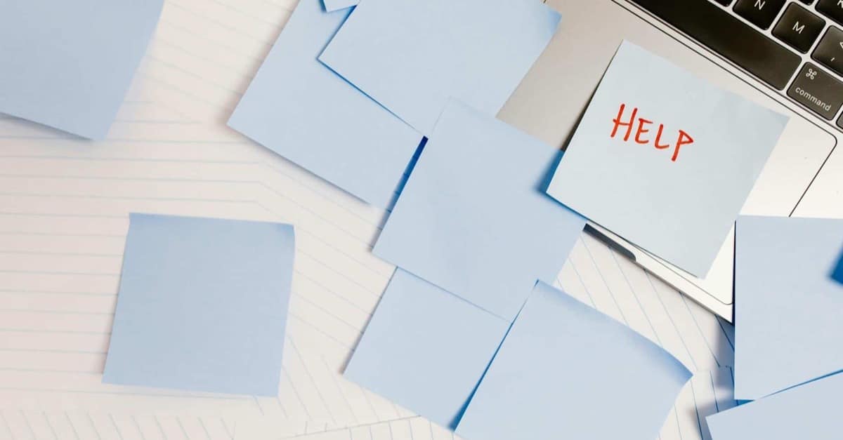 A bright desk covered with competing sticky notes beside a laptop, showing how an unranked task list loses meaning.