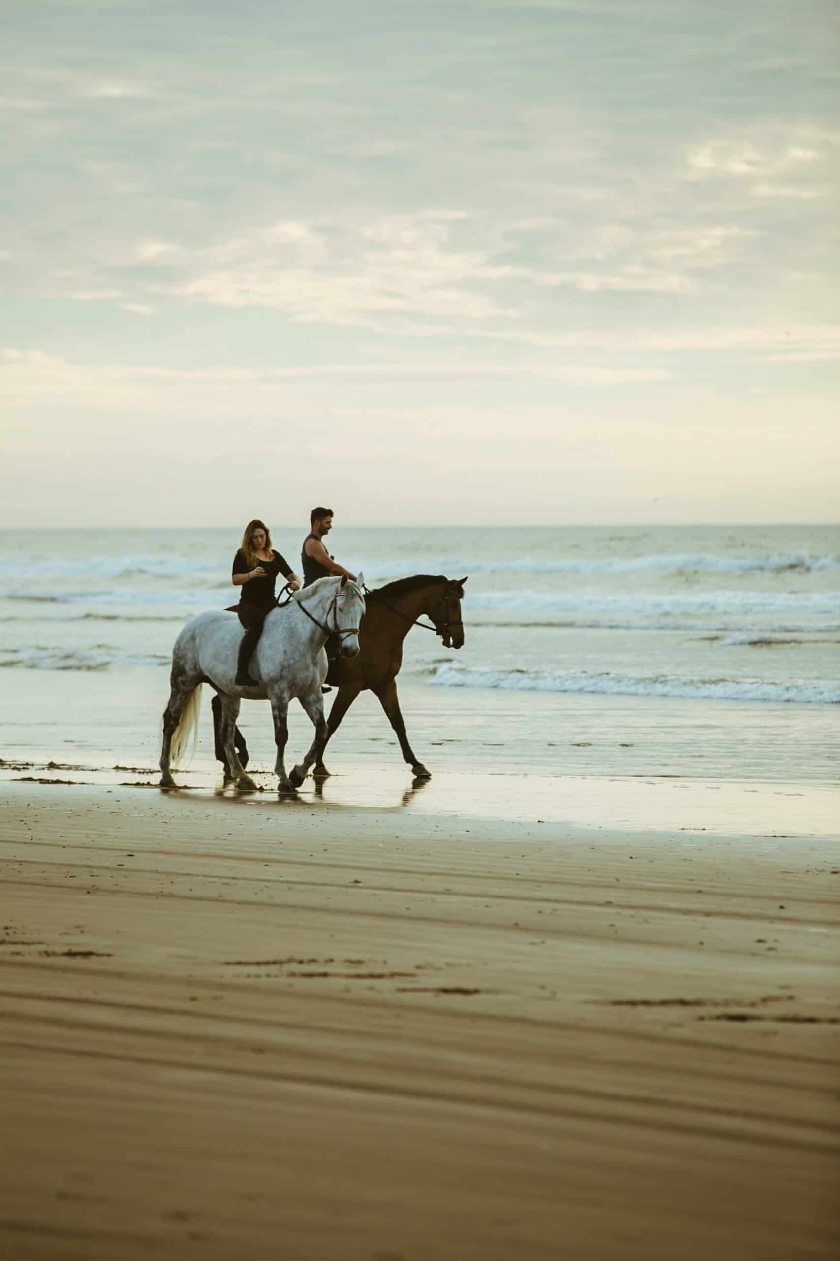 couple horseback riding at the beach