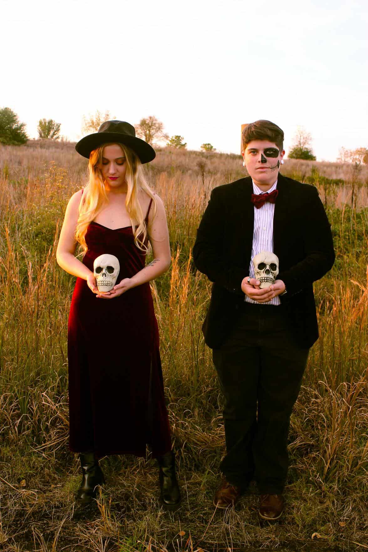couple in black outfit holding small skulls