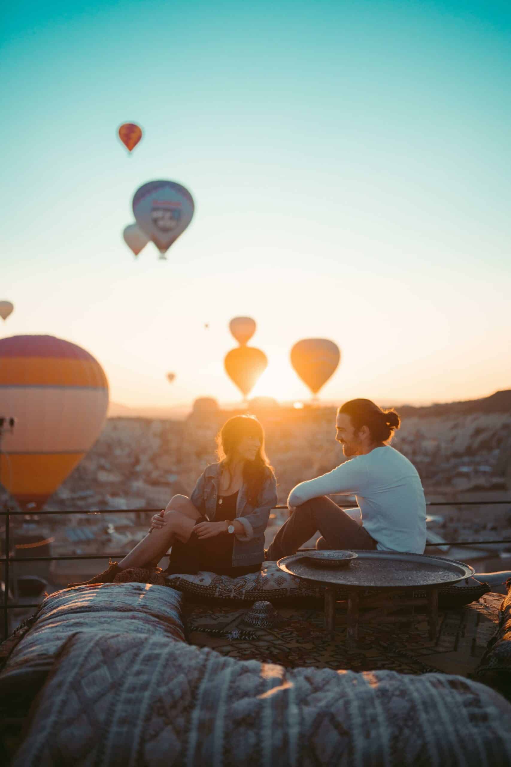 couple sitting on the rooftop watching hot air balloons