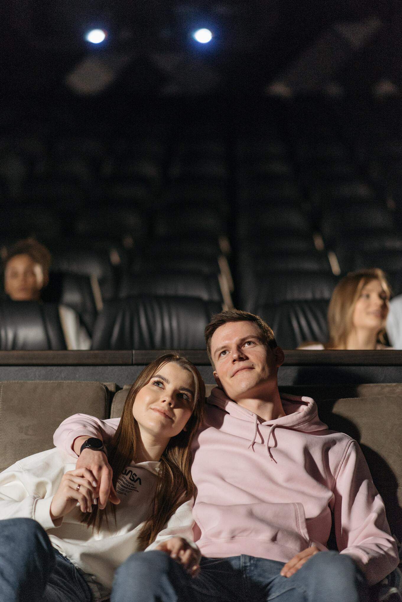 man embracing woman while watching movie in a theater