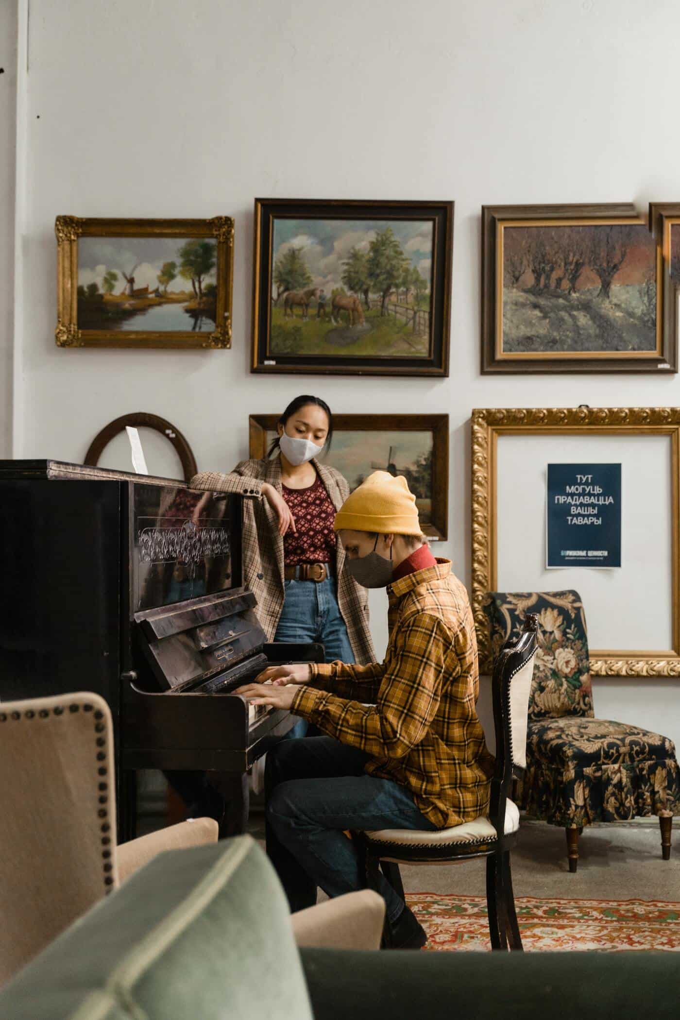 woman watching man playing an old piano in an antique shop