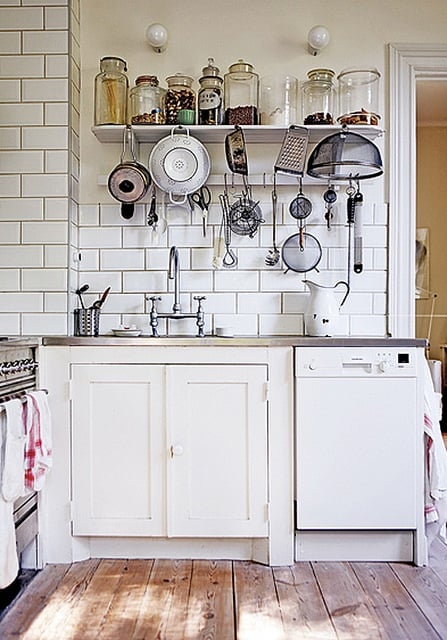 White open shelves with jars and cooking utensils atop kitchen sink