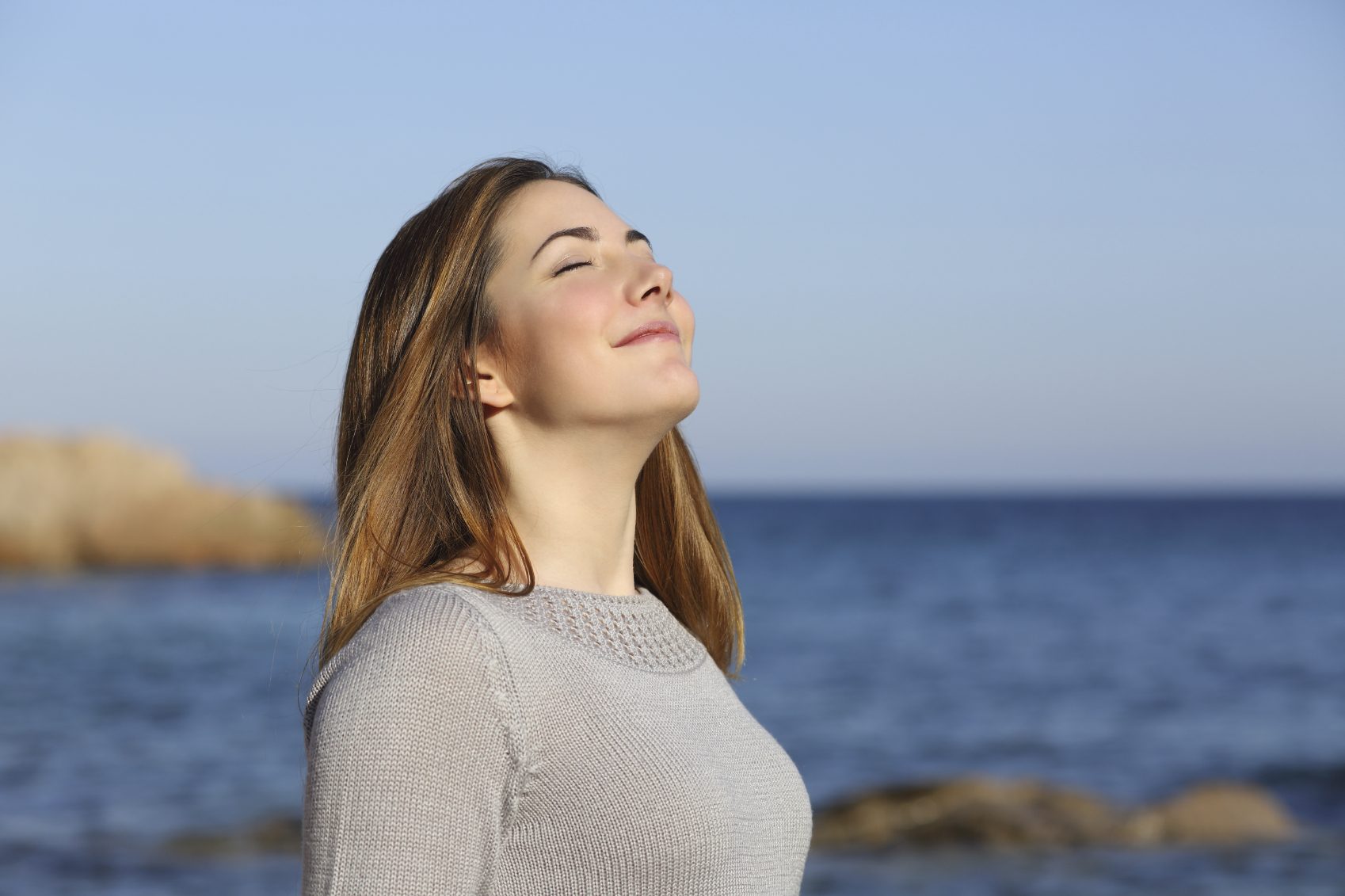 Happy woman breathing deep fresh air on the beach