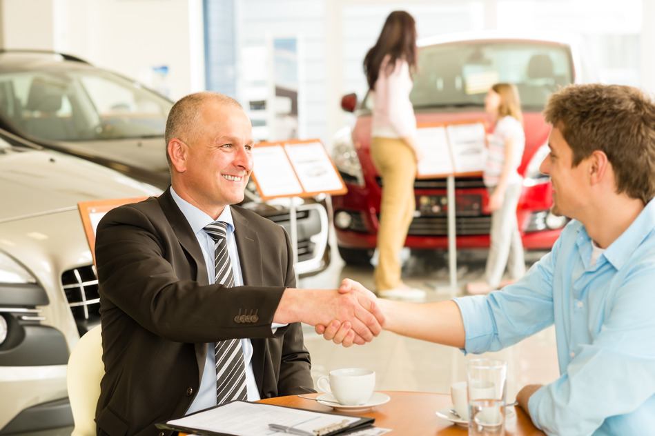 Caucasian customer and car salesman shaking hands