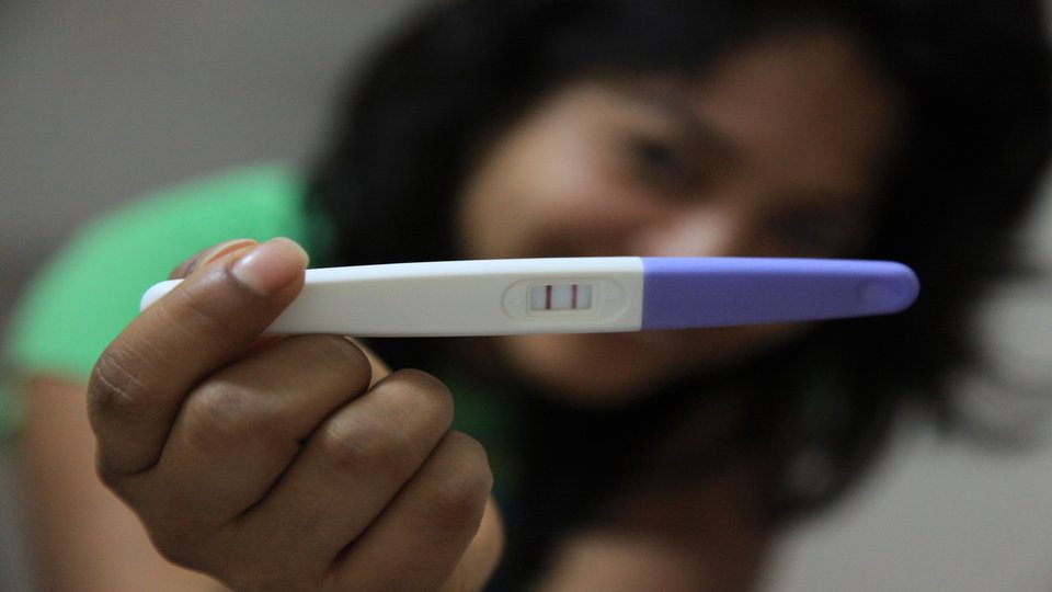 girl holding positive pregnancy test