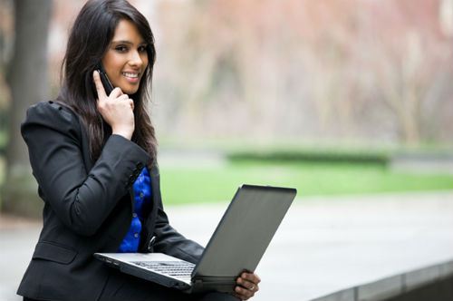 woman-working-on-laptop-talking-cellphone