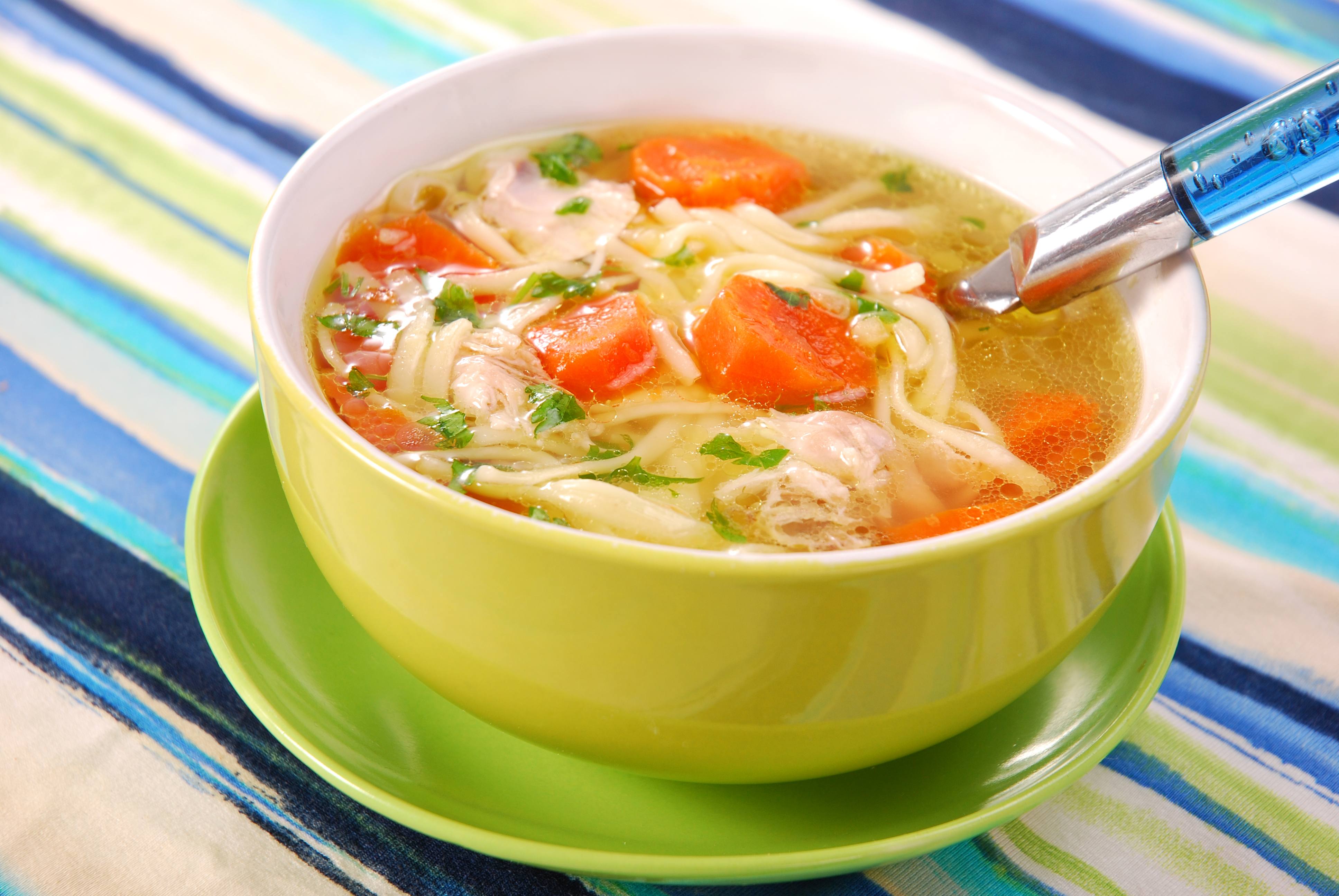 Bowl of clear chicken soup with noodle and vegetables