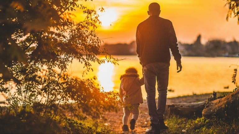 Dad walking with daughter into sunset