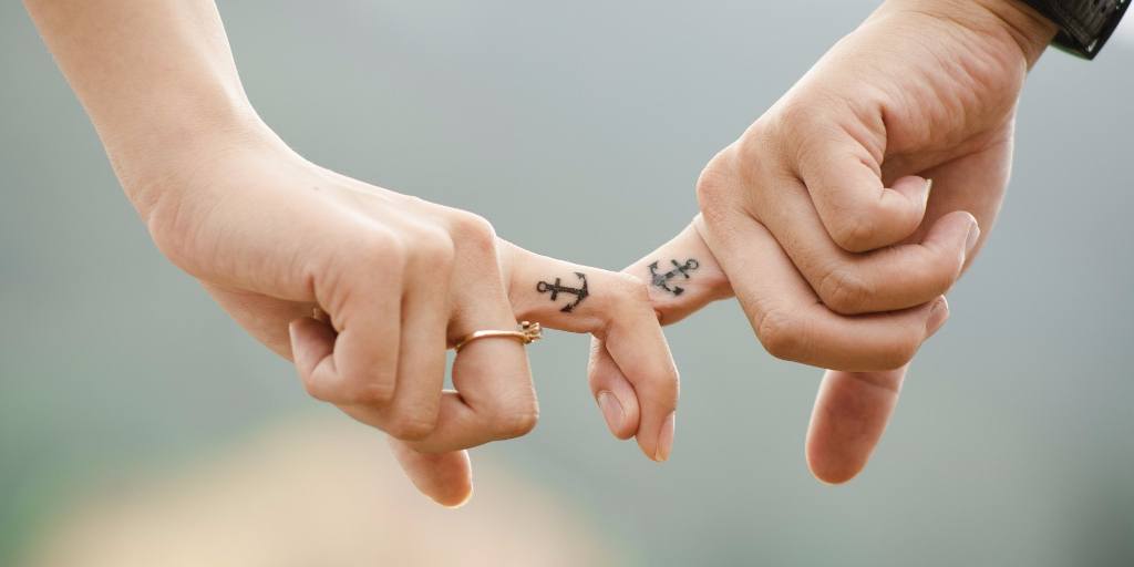 An image displays a couple holding each other's fingers