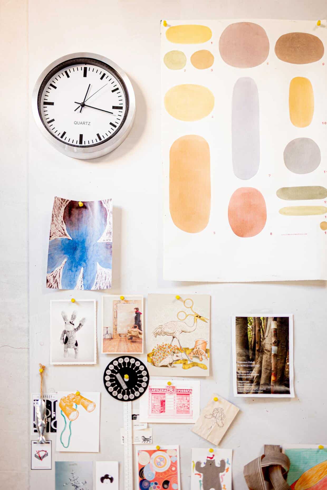 artworks posted on wall with a clock