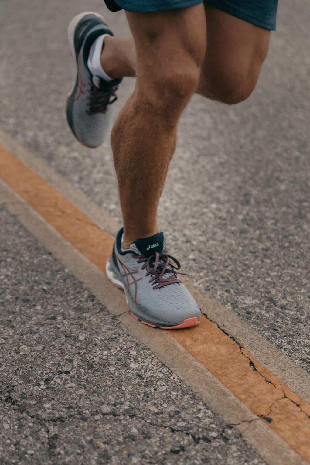legs of a man jogging on the street in rubber shoes