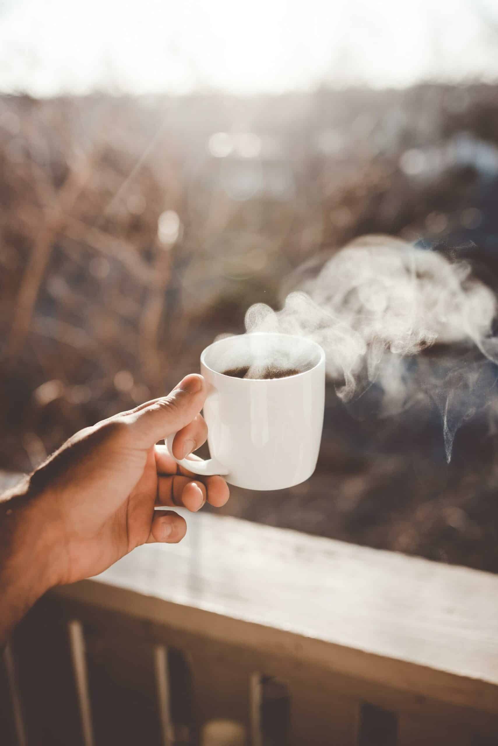 man holding out a hot cup of coffee