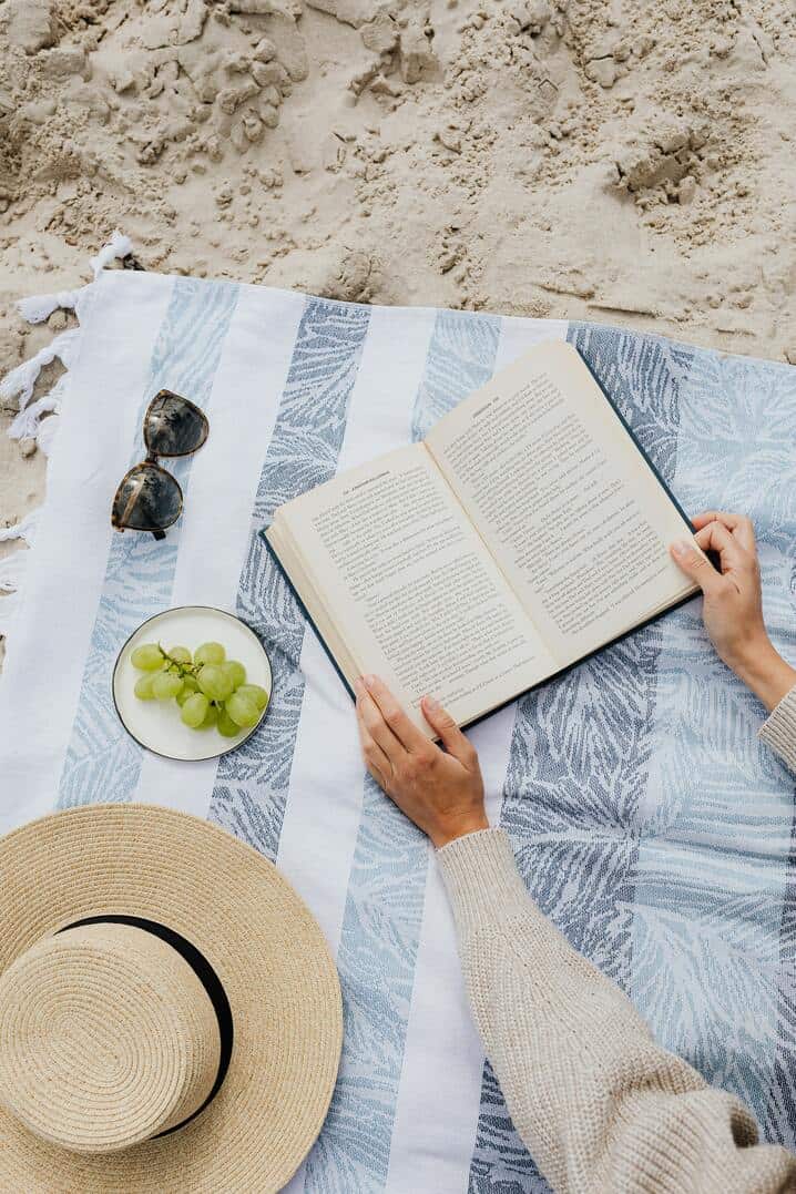 person reading a book on beach mat