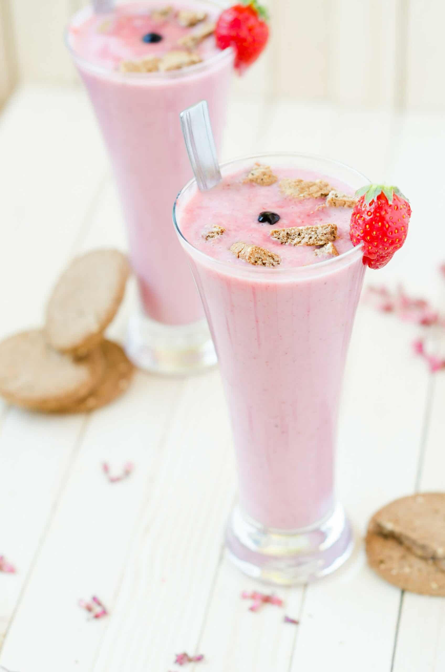 pink strawberry smoothie in tall glass topped with brown cookie bits