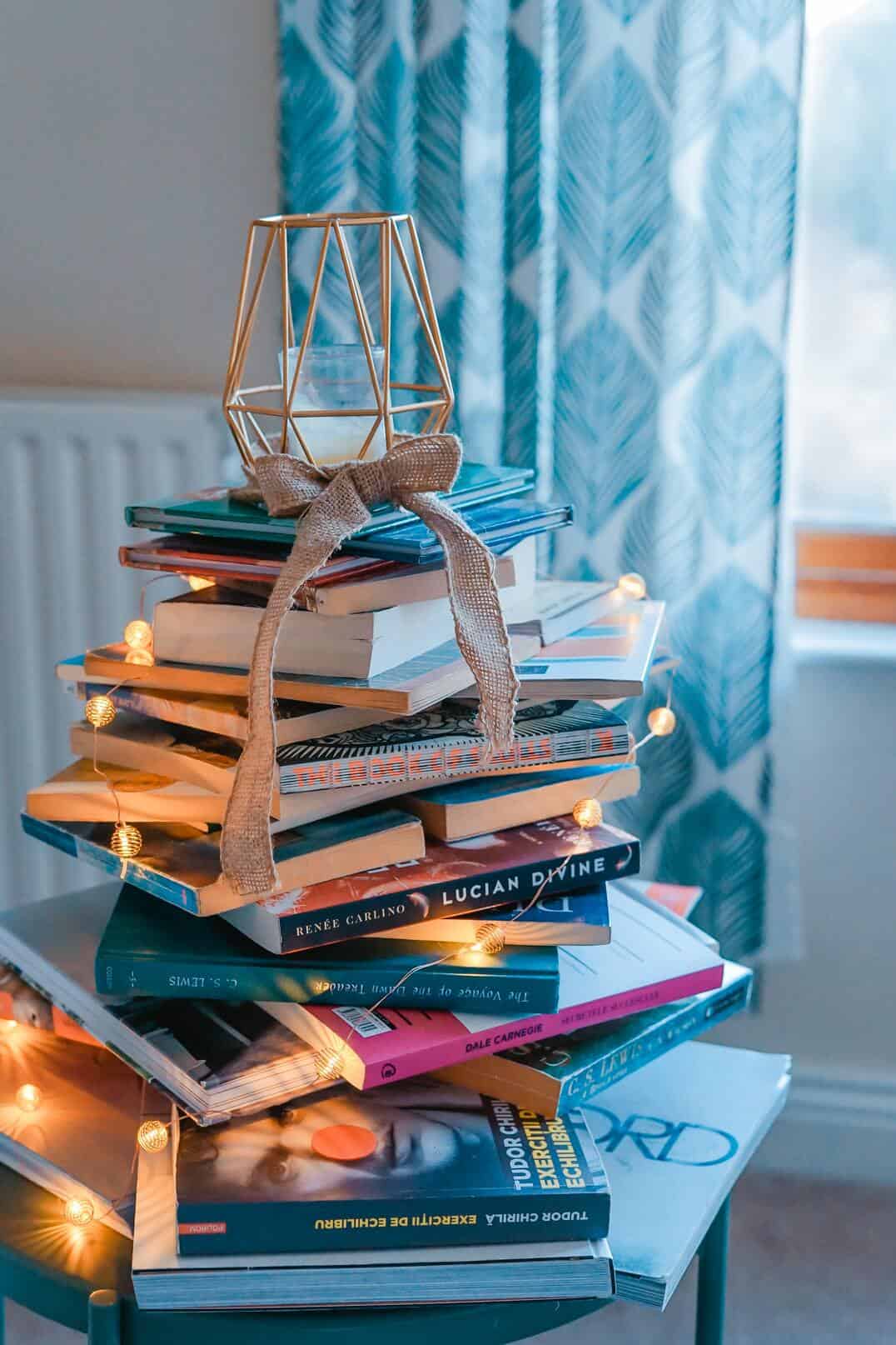 stack of books with lamp around and candle on top