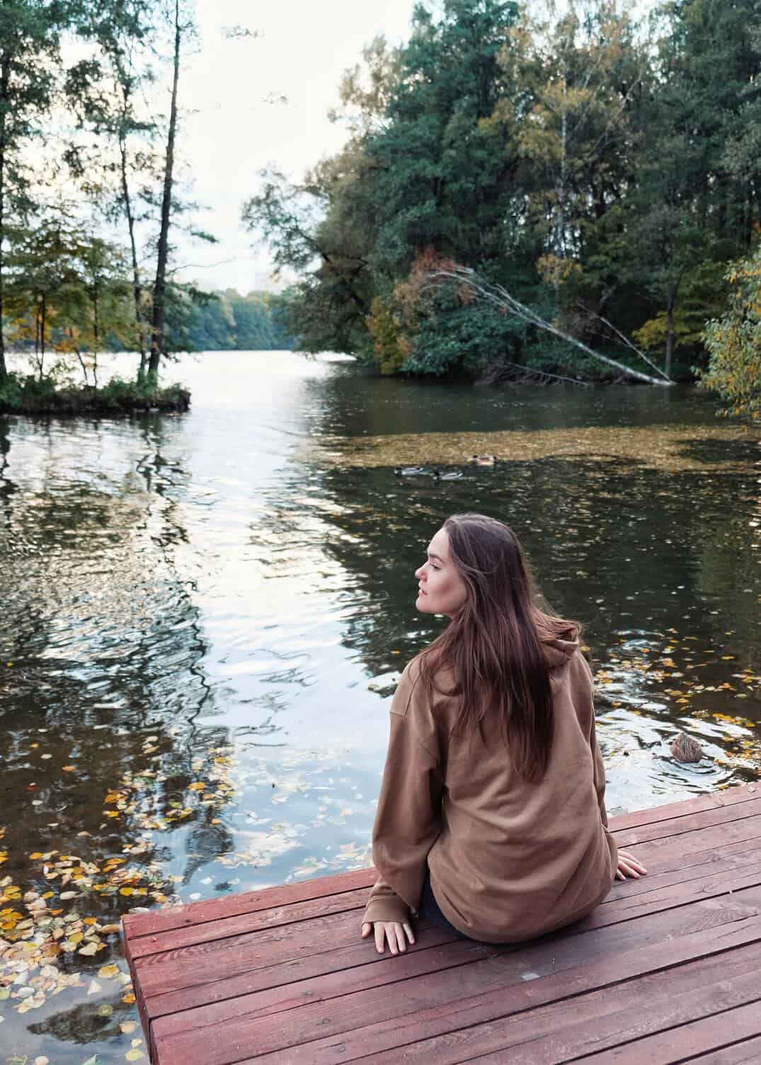 woman sitting at the edge of a bridge near lake